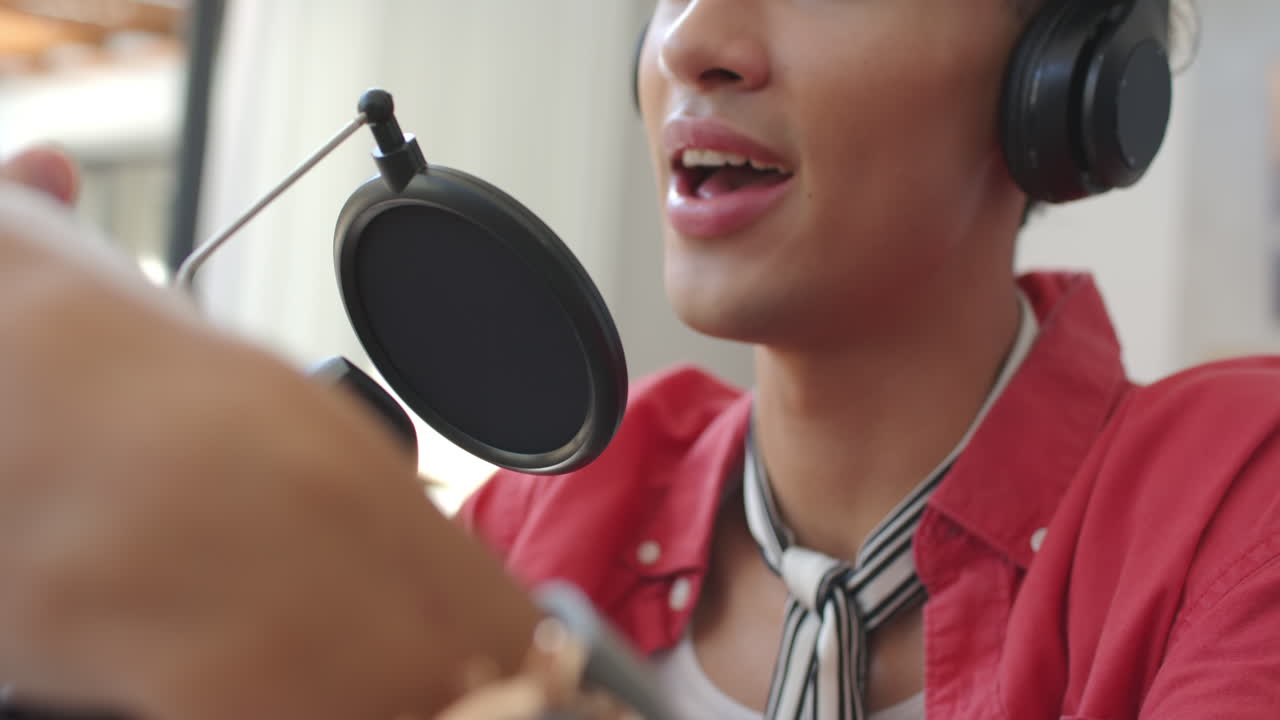 Recording podcast, person wearing headphones and speaking into microphone at home