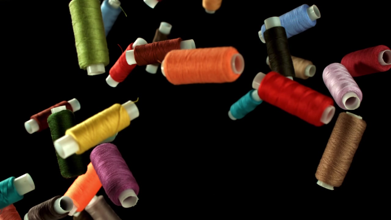 Colorful Sewing Threads Falling in Slow Motion on Black Background