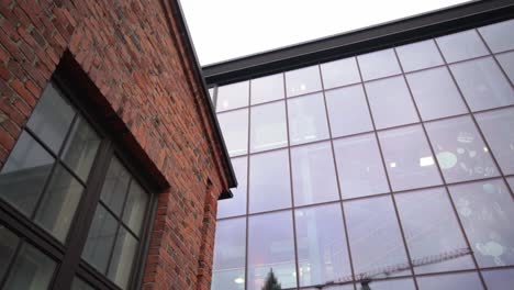 a red brick wall of an factory building in front of a modern house with glass facade in slow motion