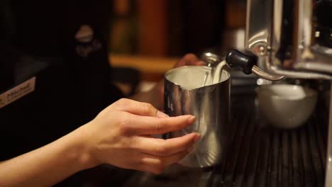 slowmo - female barista frothing milk for cappuccino - flat white - latte - close up