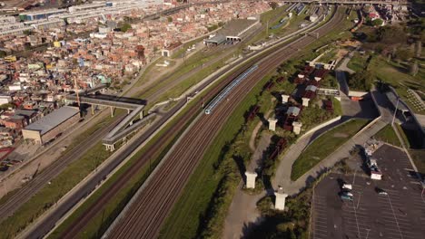 Toma-Aérea-Del-Tren-Que-Llega-A-La-Estación-De-Tren-De-Cercanías-Junto-Al-Paisaje-Urbano-De-Buenos-Aires-Durante-La-Puesta-De-Sol---Vista-Panorámica