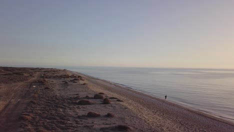 man running on the beach. orbital shot with drone