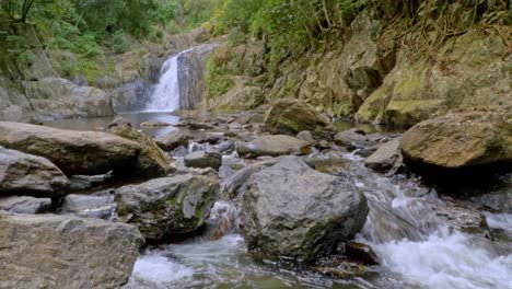 Agua-Que-Fluye-Hacia-Un-Arroyo-Rocoso-Con-Cascadas-De-Cristal-En-El-Fondo
