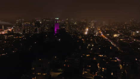 Aerial,-4th-of-July-fireworks-at-night-in-San-Francisco,-Coit-Tower-in-view