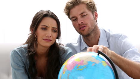 pareja mirando el globo y eligiendo el destino de viaje