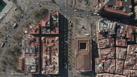 Top-down-footage-of-vehicles-passing-through-complex-road-intersection-in-city.-Flying-above-blocks-of-buildings.-Barcelona,-Spain