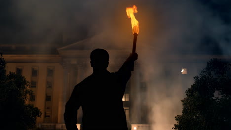 silhouetted figure holding a torch at night