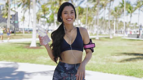Relaxing-sportswoman-with-bottle-of-water-in-park