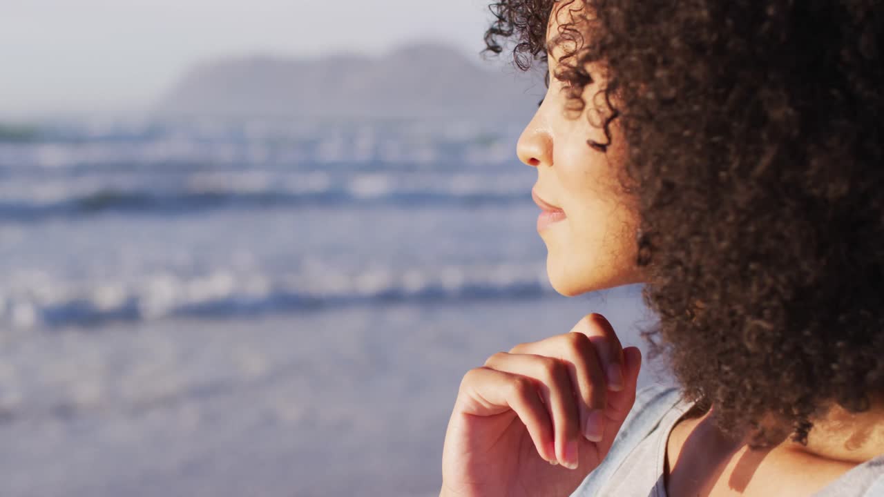 de primer plano de afroamericano con la mano en la barbilla sonriendo en la playa
