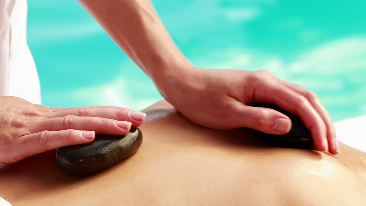 미용 치료사 는 여자 들 의 등 을 뜨거운 돌 로 문지르고 있다