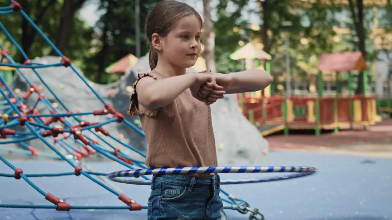 chica caucásica jugando con salto de plástico en el patio de recreo.
