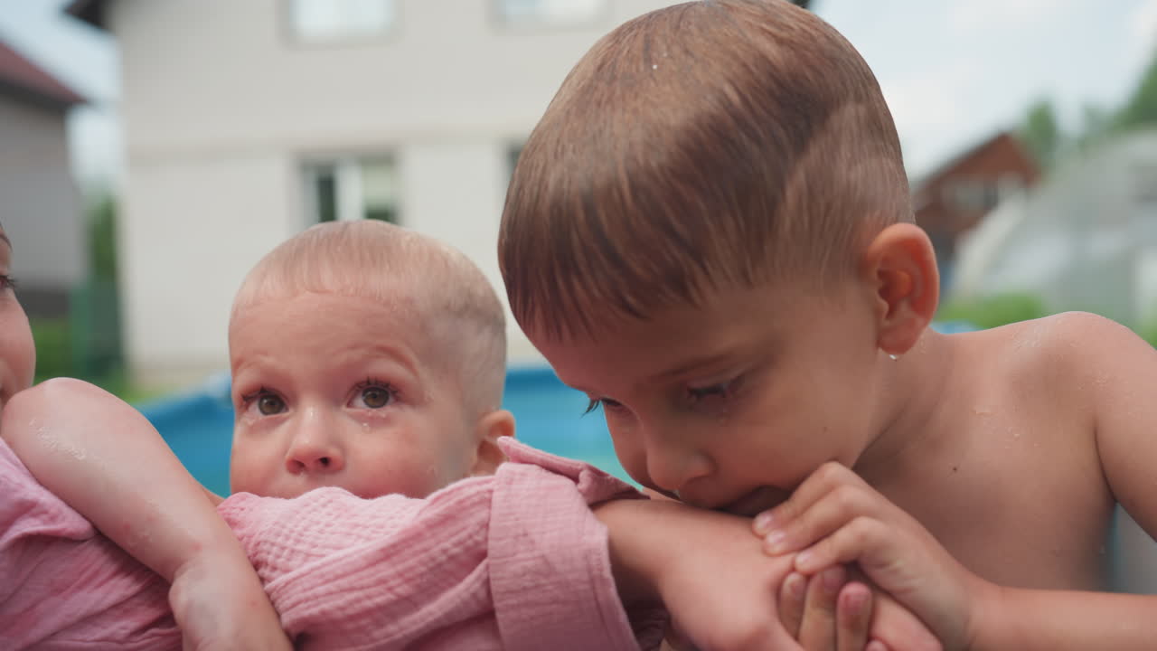 Sibling Caring Scene, Older Sibling Shares Tender Kiss With Baby, Gentle Brother Holds And Kisses Baby Between Pink Towel, Caring Older Brother Leans In To Softly Kiss And Protect Infant