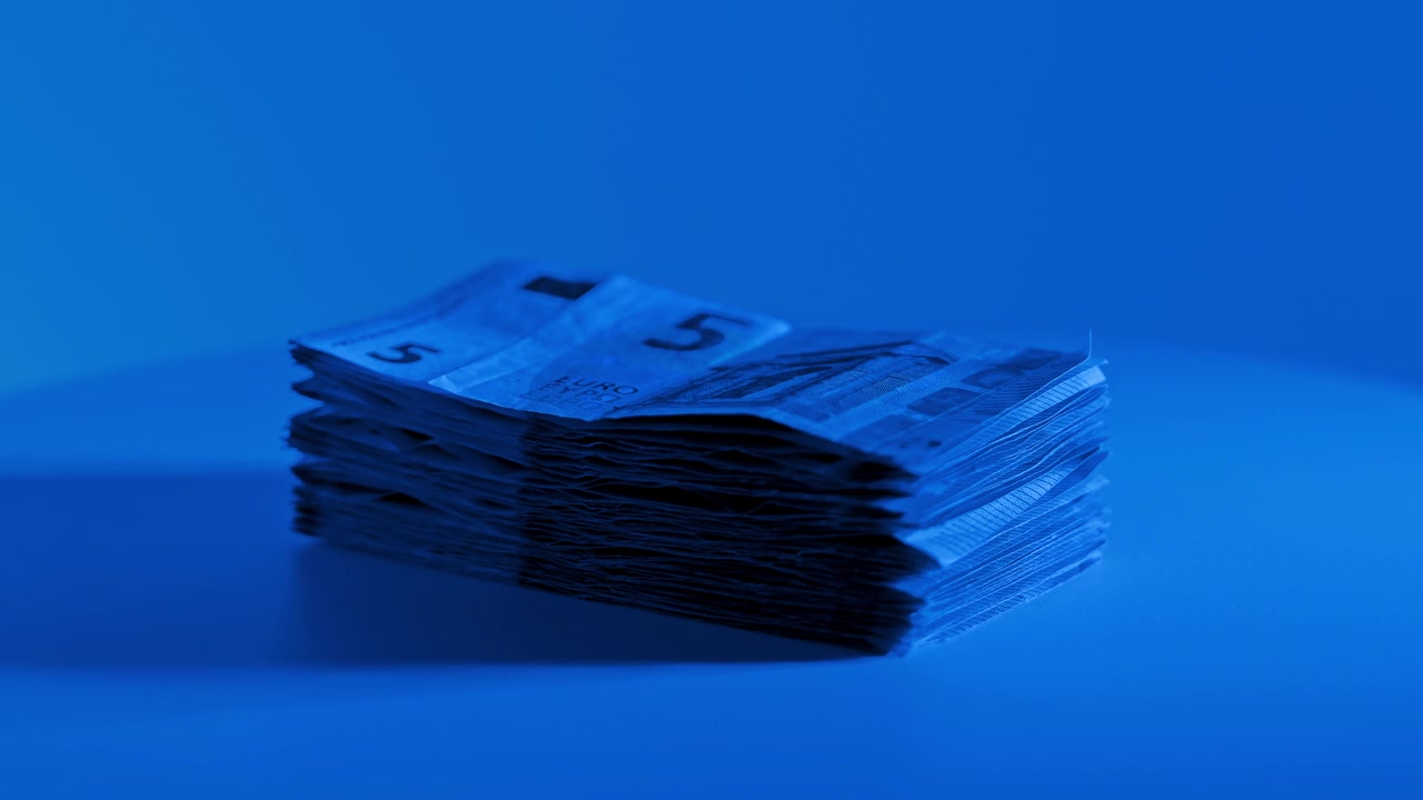 Mavi ışık altında dönen euro nakit destesi finansı, tasarrufu ve zenginliği simgeliyor.