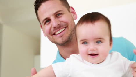 padre sonriente ayudando a su bebé a levantarse