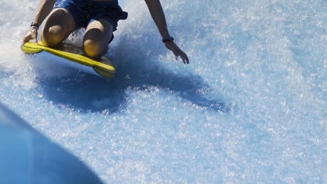 boy riding wave machine on boogie board slow motion