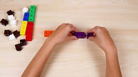 hands assembling colorful cubes on a table