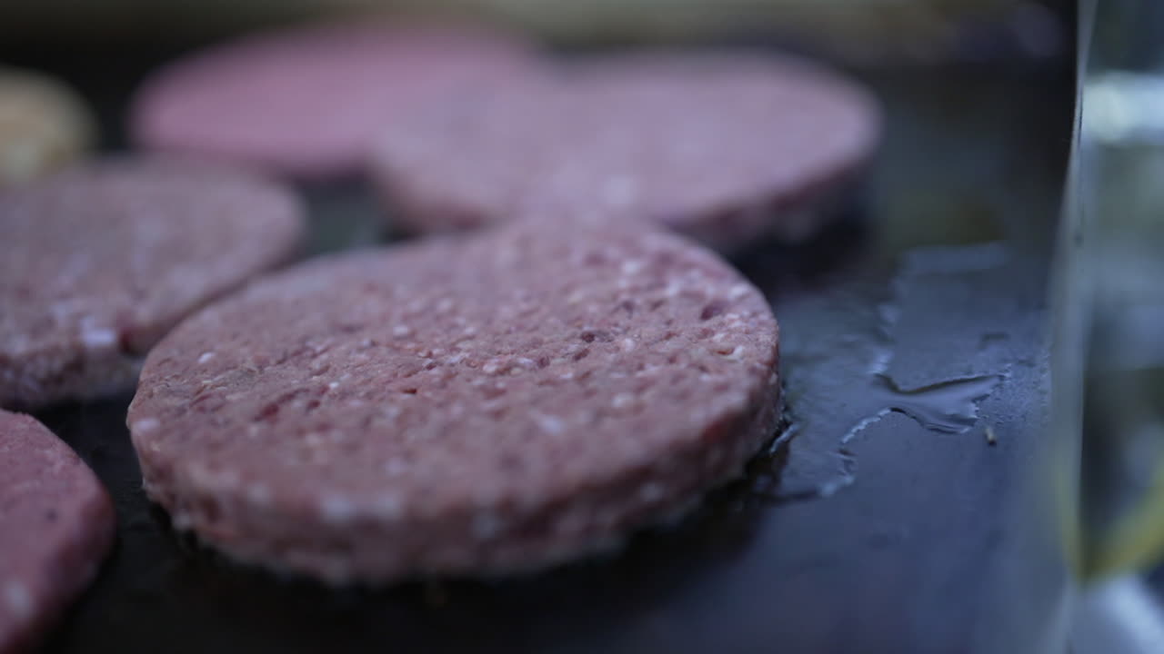 Raw hamburger patties cooking on a griddle