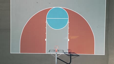 Aerial-drone-bird's-eye-view-over-half-of-a-colorful-basketball-court-on-a-bright-sunny-day