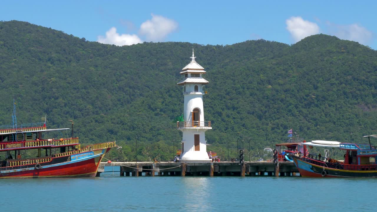 등대가 있는 부두에 정박해 있는 배들의 와이드 샷