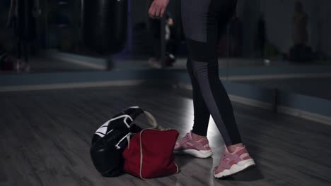Young-fit-woman-entering-a-fitness-club-with-a-bag-and-boxing-gloves-and-preparing-for-the-training-in-a-boxing-club.-Shot-in-4k