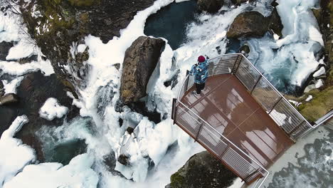 vista superior de un turista en la plataforma de observación de una cascada cubierta de nieve en la ciudad de geiranger, noruega occidental