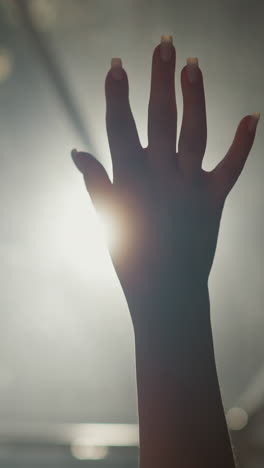 woman palm opens and closes in dark room closeup. lady hand silhouette does graceful gestures at glowing backlight in dark studio. body language signs