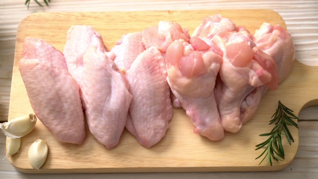 Alas de pollo crudo fresco sobre tabla de madera con ingredientes