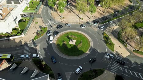 a flyover captures the bustling rotary in périgueux, france, under the bright sunshine of a clear afternoon, showcasing the lively traffic and vibrant city life