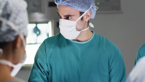 Video-of-caucasian-male-surgeon-talking-with-colleagues-during-operation-in-operating-theatre