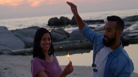 Happy-young-mixed-race-couple-having-fun-with-sparklers-at-beach-4k