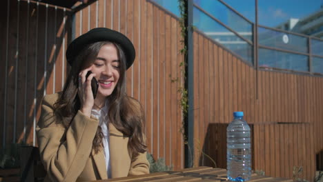 mujer hablando por teléfono en un café al aire libre