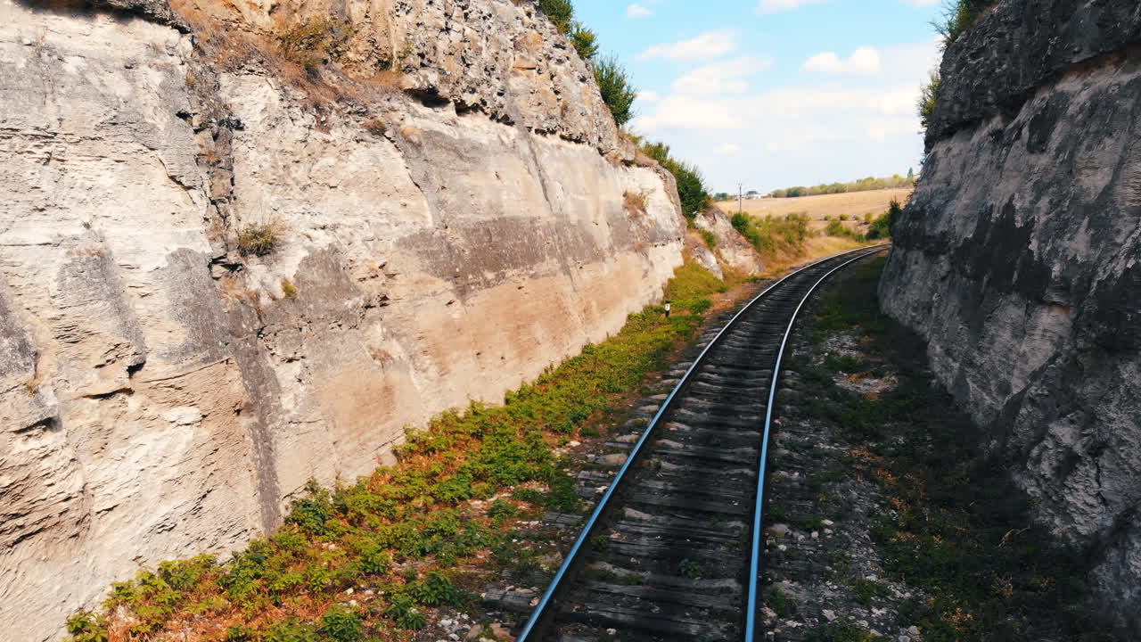 Railway between stones walls with a bridge in the fields of Moldova. Aerial drone view. Sunny day