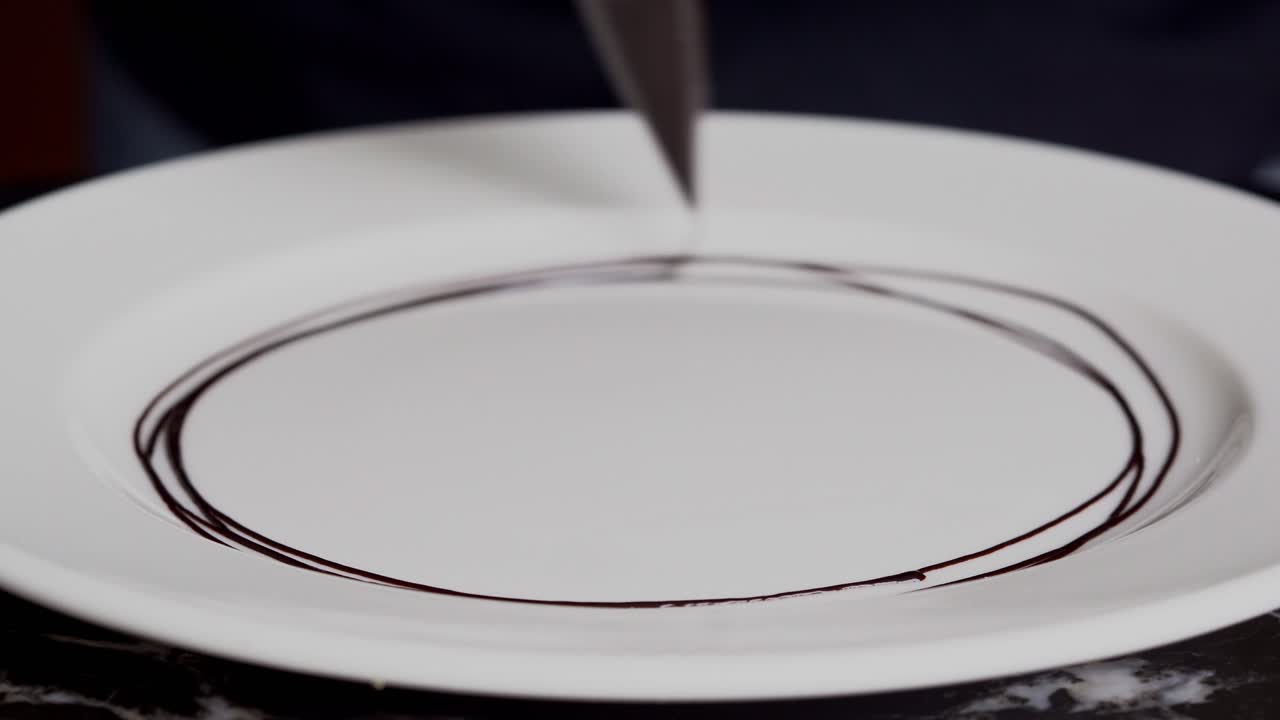 한 사람이 초콜릿 소스와 조각으로 접시를 장식합니다. 근접 촬영, 입 촬영