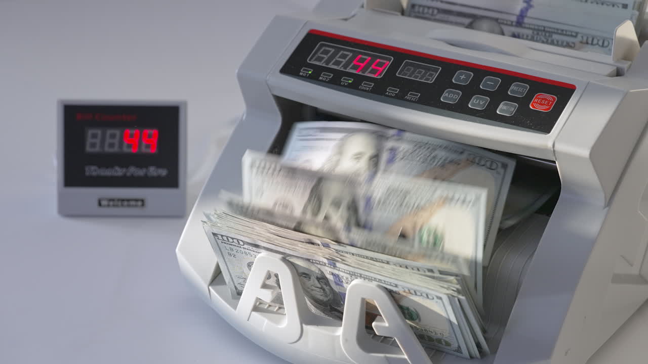 Male puts a wad of US dollars into money machine. Equipment for financial operations working. High angle view. Close up.