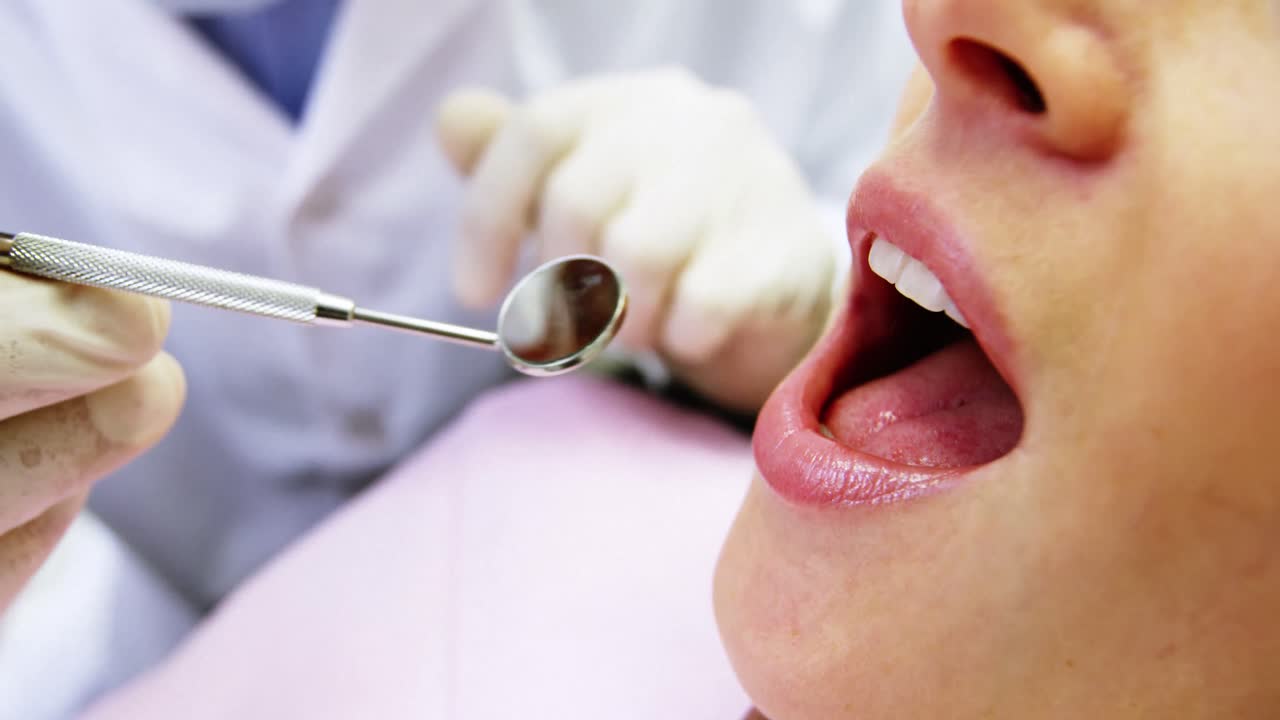 Dentist examining a female patient with tools