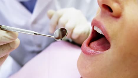 dentist examining a female patient with tools