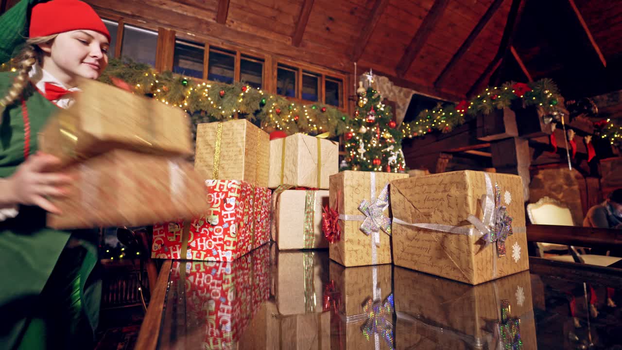 Gifts for Christmas on the table. Two happy elves putting presents on a desk at Christmas decorated room. Pile of boxes with presents for children.