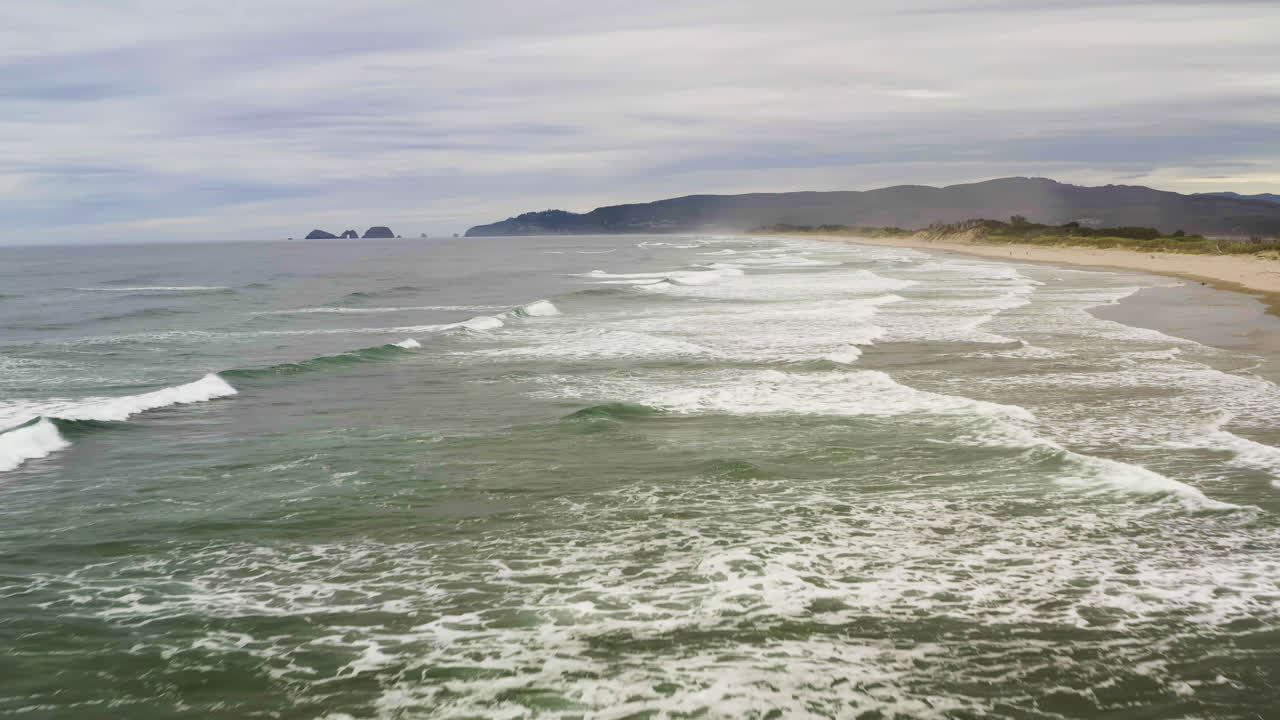 las olas del océano se rompen, se estrellan y dejan un rastro de espuma blanca en el agua, en la costa de oregón.