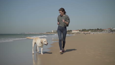 Young-woman-having-fun-with-dog-on-seashore