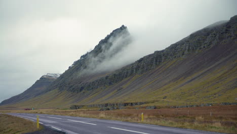 fog quickly rolls down mountain in iceland next to highway