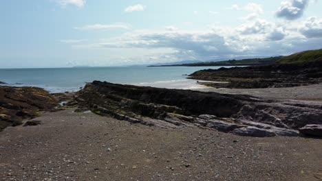 Aerial-view-Traeth-Lligwy-Jurassic-rocky-weathered-rugged-Anglesey-coastal-shoreline,-low-dolly-right