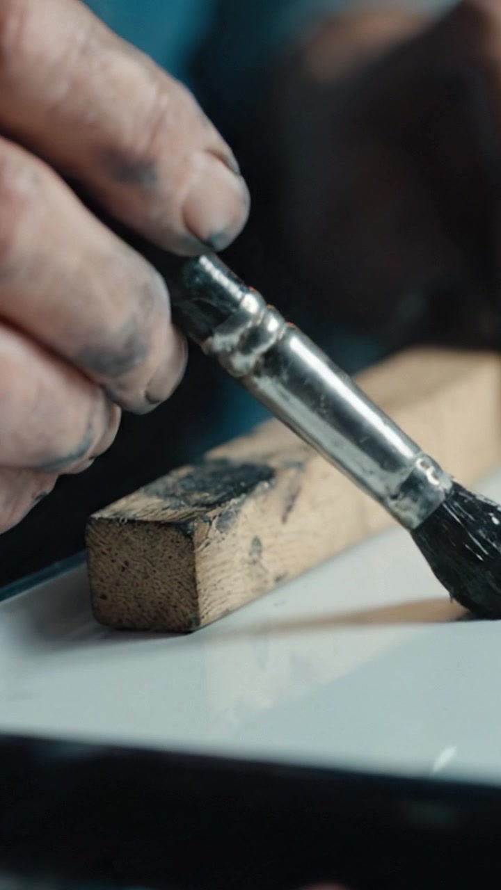 Detailed Close-Up of a Hand Painting Wooden Surface with Brush, Capturing the Intricacy of Craftsmanship and Artistic Expression in Every Stroke
