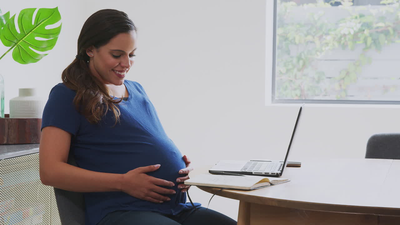 가정에서 일하는 테이블에서 노트북을 사용하는 임신한 여성