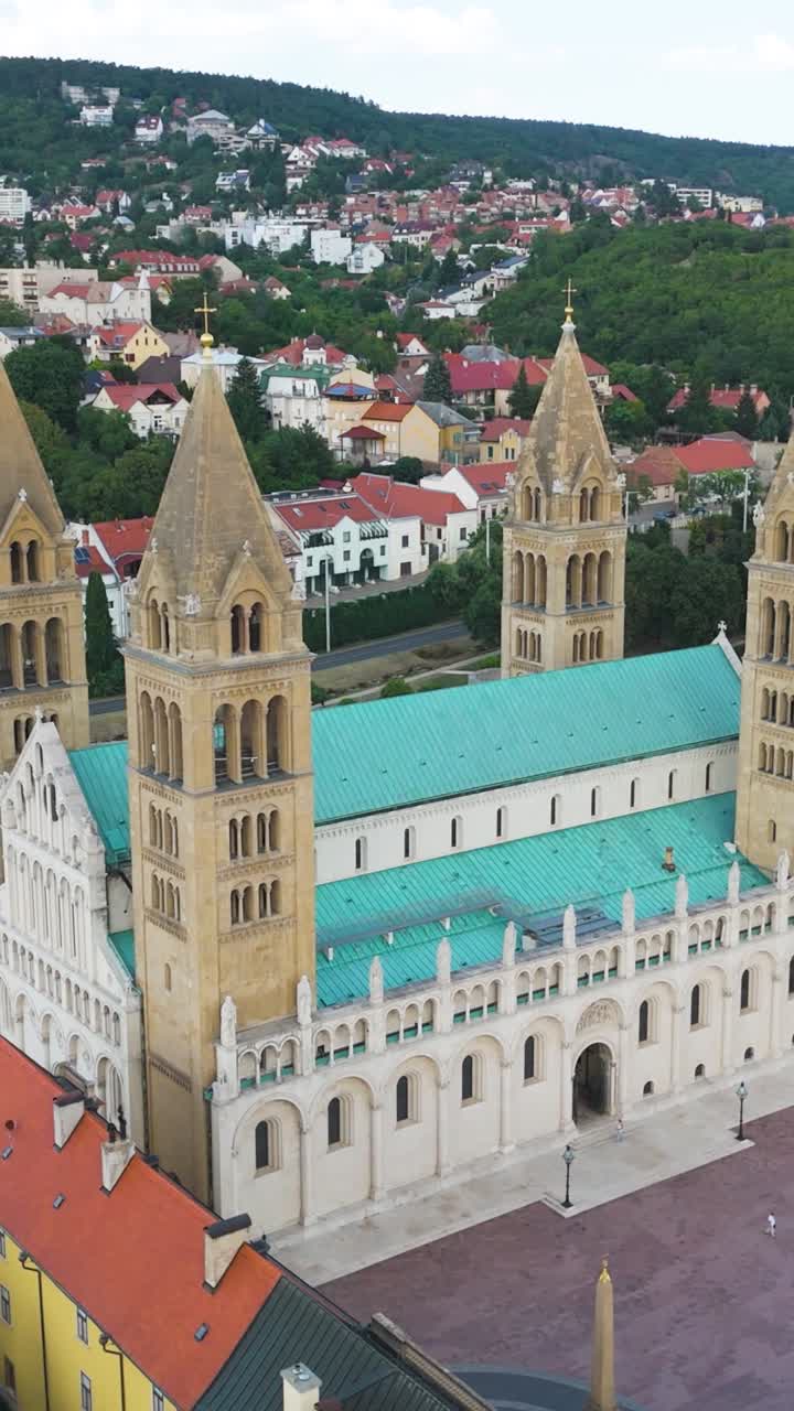 Vertical drone footage capturing Pécs Cathedral, showcasing its towers, and surrounding urban scenery