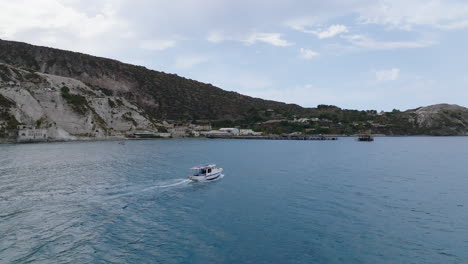 4k aerial of lipari abandoned pomice mine tracking boat in the foreground, italy