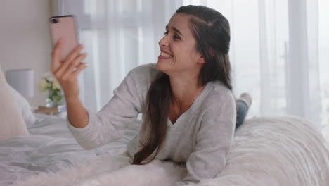 beautiful-woman-having-video-chat-using-smartphone-chatting-to-friend-enjoying-conversation-lying-on-bed-relaxing-at-home