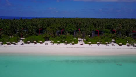 pan aéreo, la gente nada en el resort de playa turquesa maldivas con bungalows junto al mar