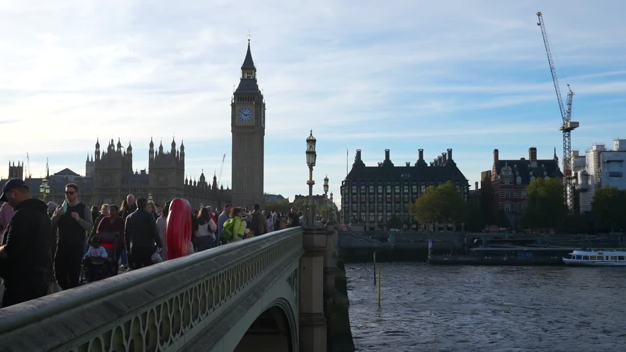 Busy Westminster Bridge with people and birds, Big Ben and Parliament in view on a sunny day
