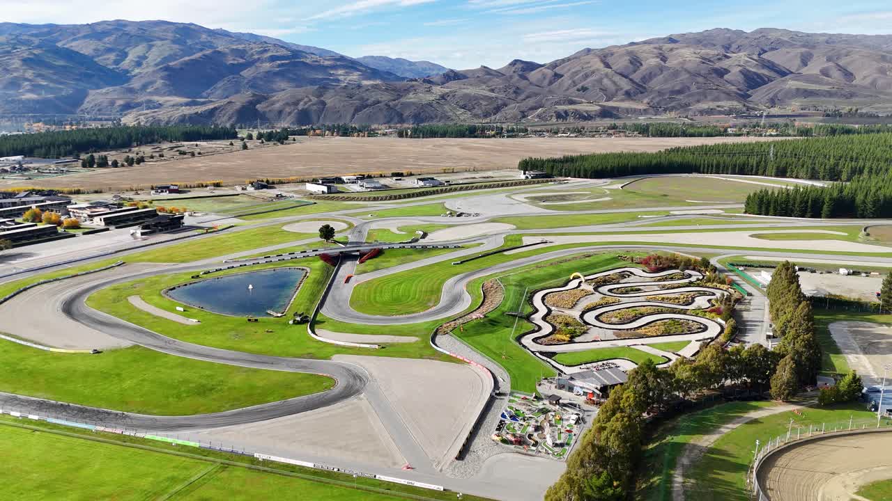 Aerial footage captures go-karts racing on a scenic track in Cromwell, New Zealand, under clear skies with mountainous backdrop