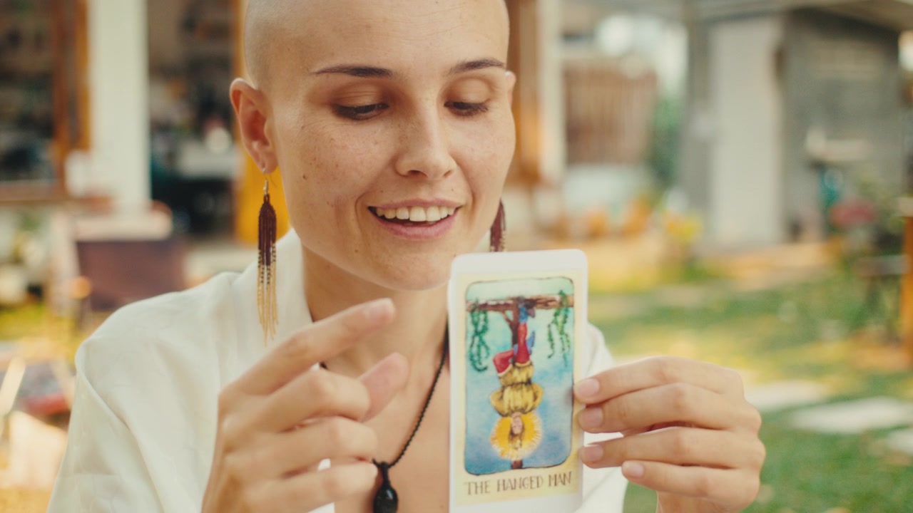 Mujer sosteniendo y examinando la carta del tarot El Colgado